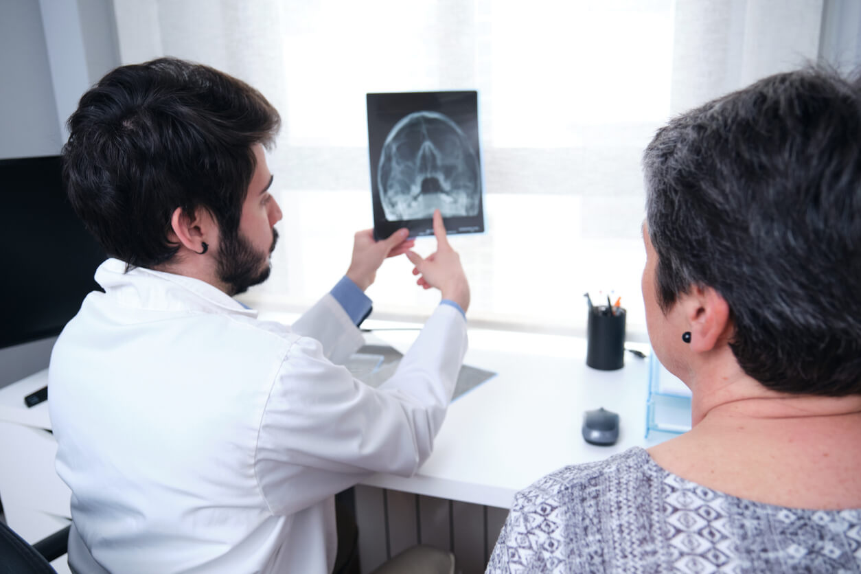 Young doctor examining x-ray of the skull, sinuses with a mature woman patient.